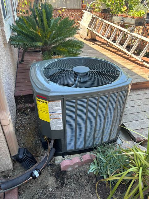 An air conditioner is sitting in the dirt next to a ladder.