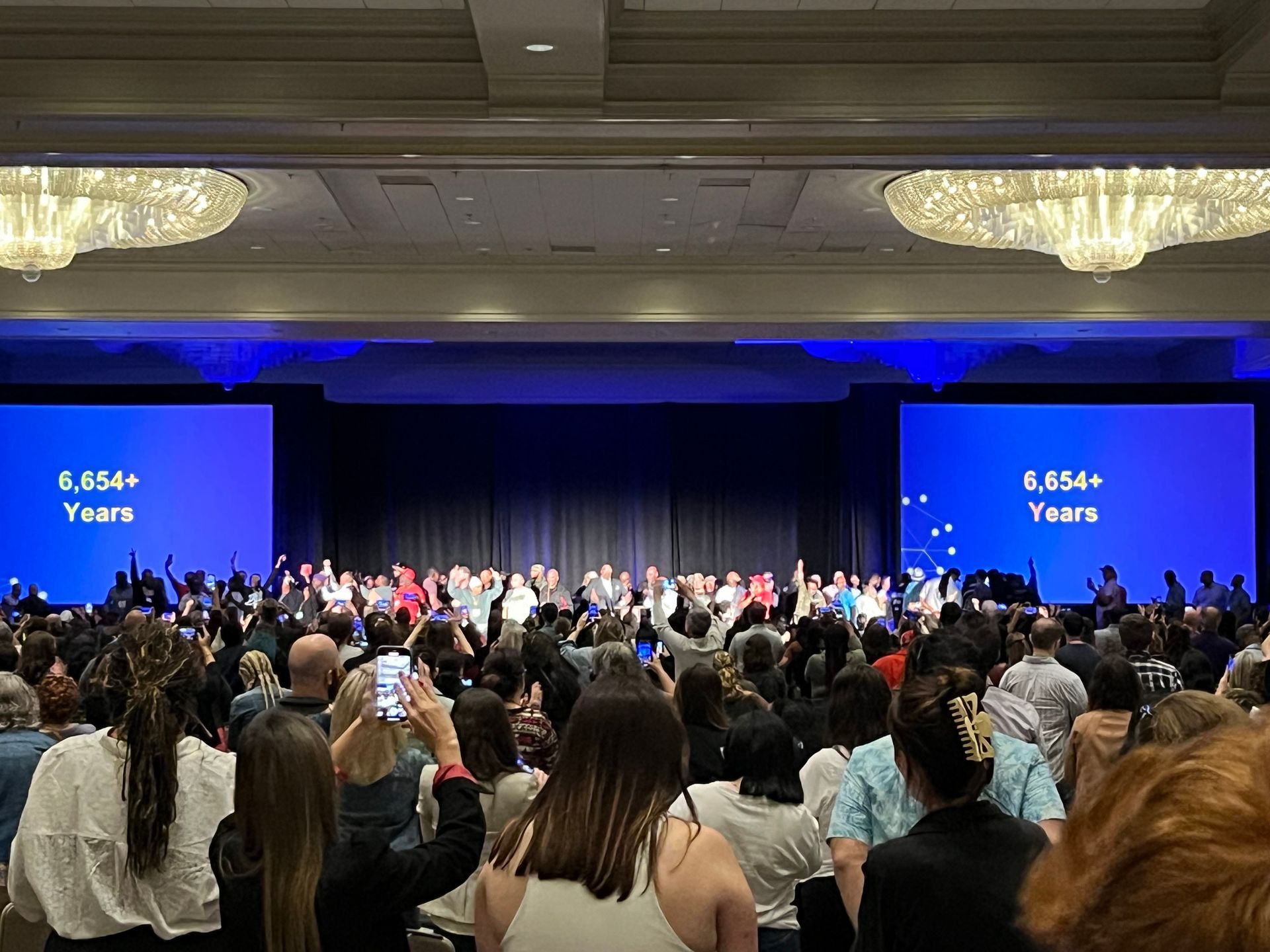 A large group of people are sitting in front of a stage.