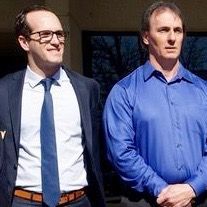 Two men in suits and ties are standing next to each other.