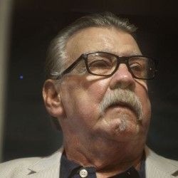 A man with glasses and a mustache is looking up.