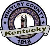 The logo for whitley county kentucky is a purple circle with a ribbon around it.