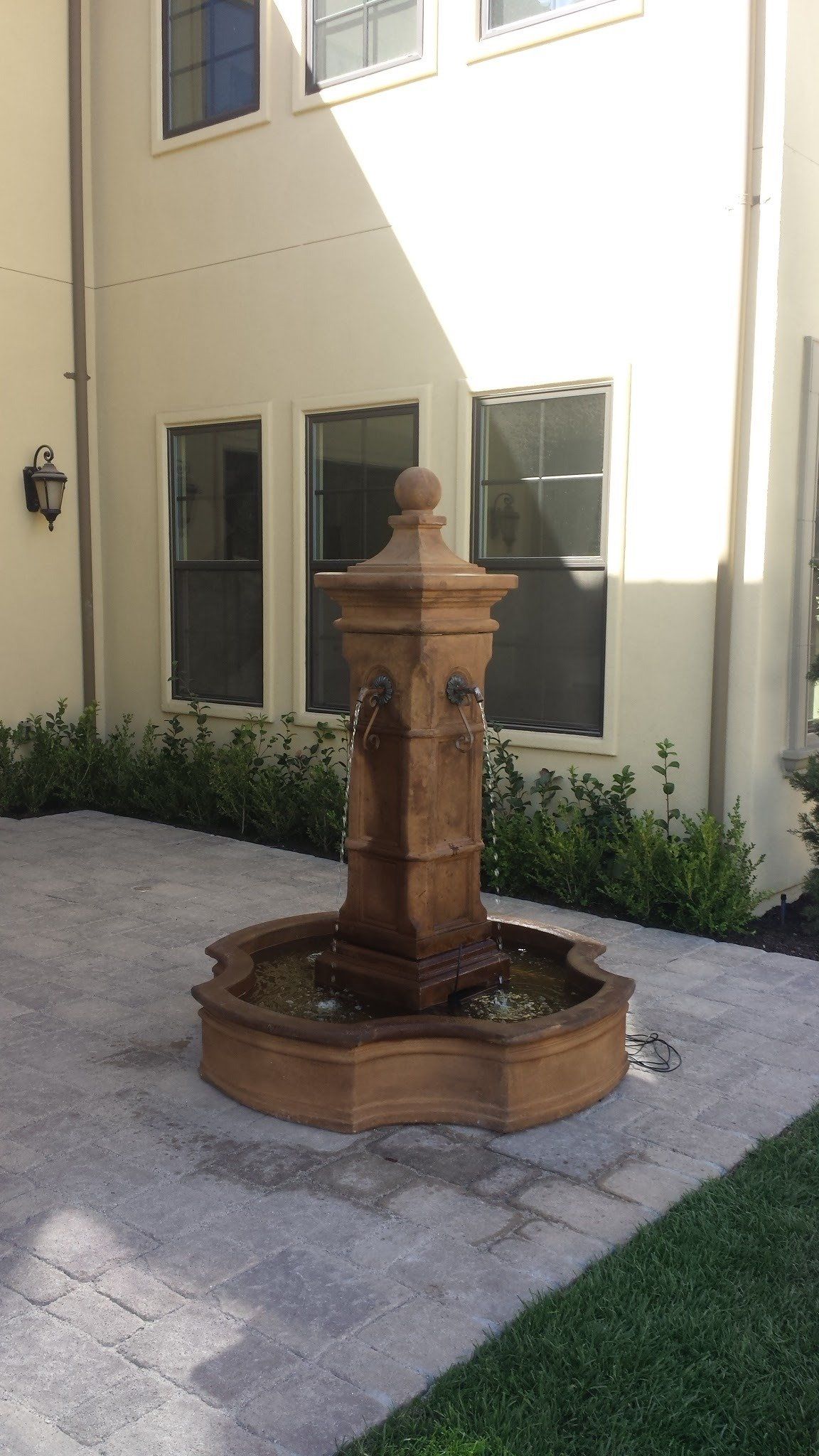A fountain is in the middle of a courtyard in front of a building.