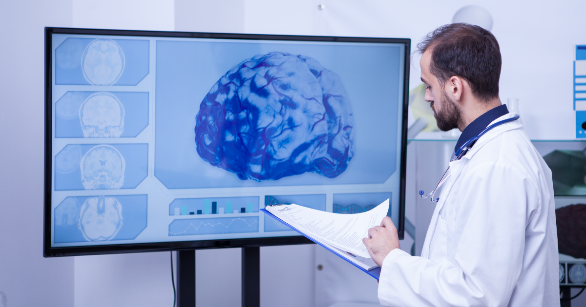 Doctor reviewing brain scan on a large monitor in a medical office