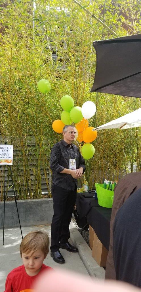 Man in black shirt standing in front of colorful balloons at Raise Your Glasses 2019 Event