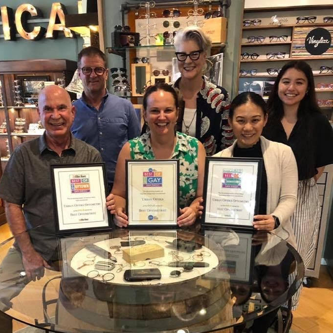 Six team members posing with three framed award certificates