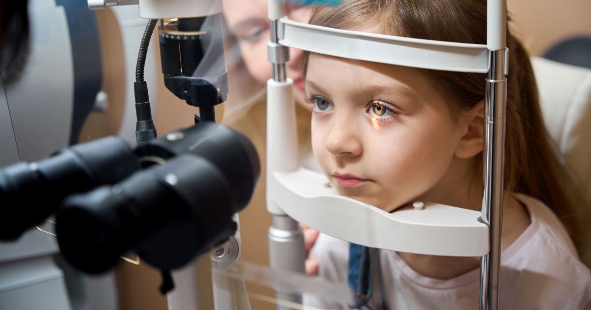A little girl with her face in a device is getting her eyes examined.