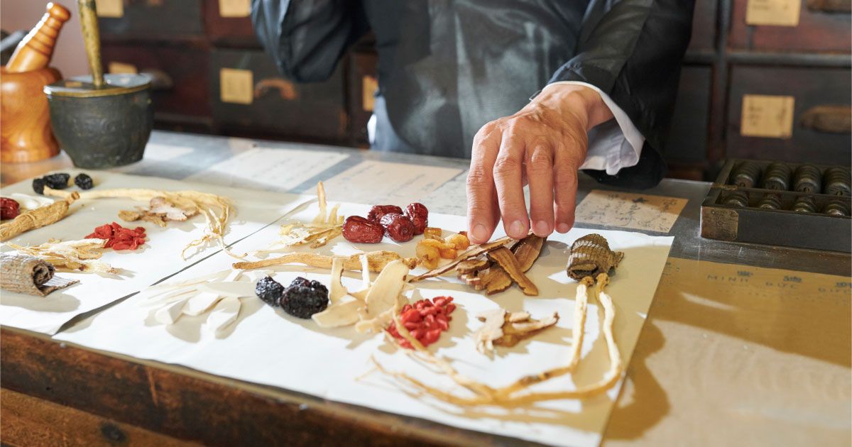 A man is sitting at a table with a tray of herbs on it.