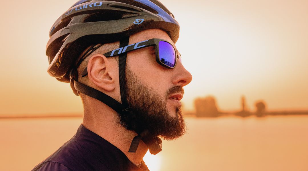 Man with wrap around sunglasses and a helmet on.
