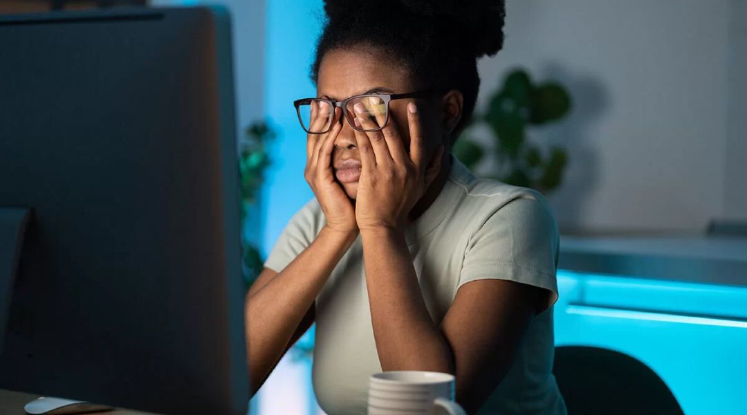 Woman rubbing her eyes while working at the computer