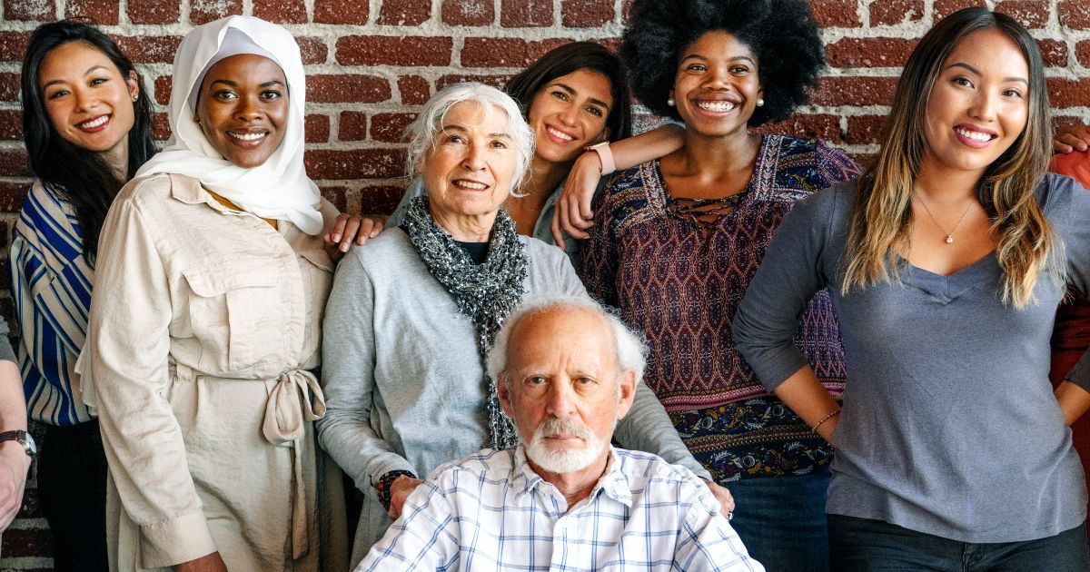 A group of multi-racial people are posing for a picture in front of a brick wall.