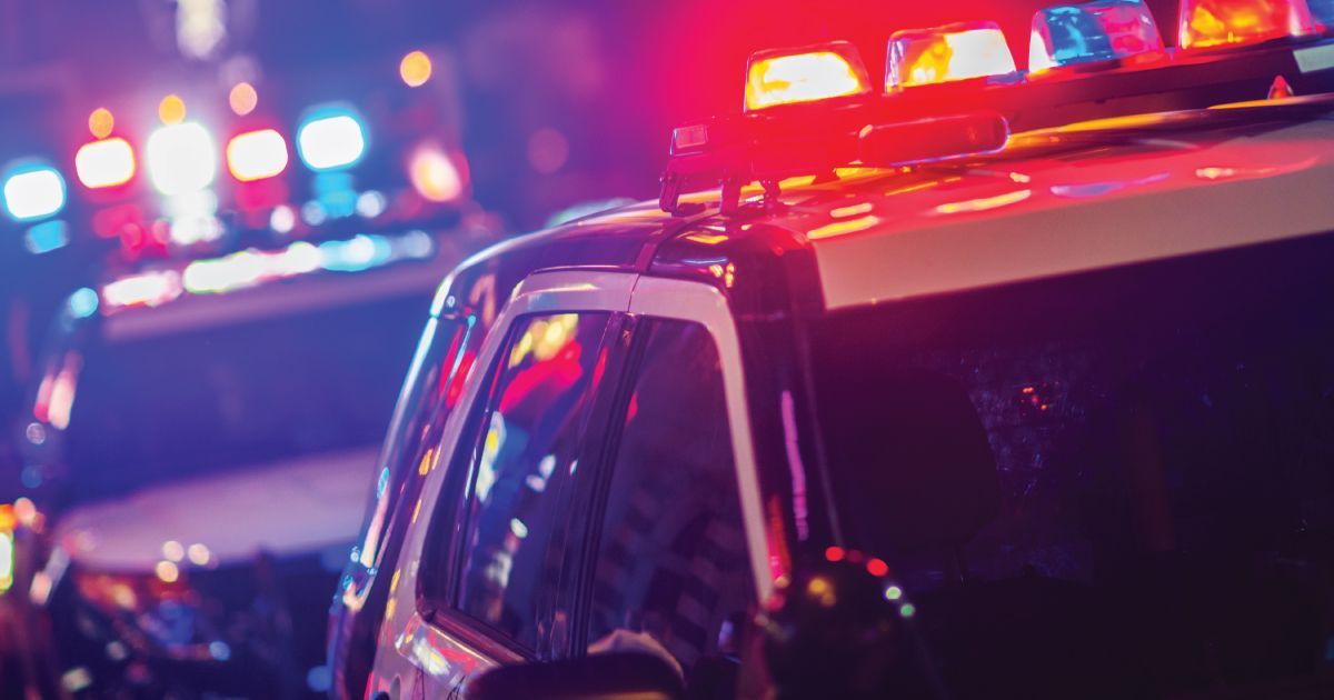 Police cars with flashing red and blue lights at night on a city street