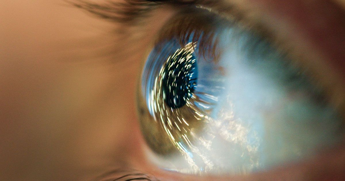 A close up of a person 's eye with a reflection of small rays of light
