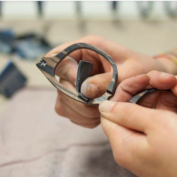 Artisan sanding a pair of wooden glasses during production