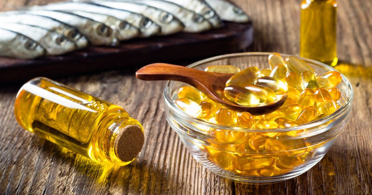A bowl of fish oil pills with a wooden spoon in it on a wooden table