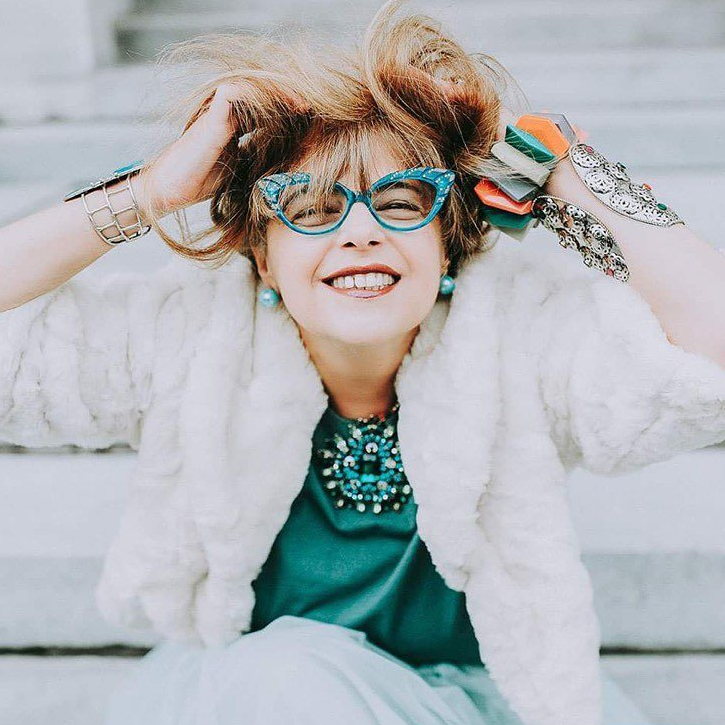 Woman in a white and turquoise outfit wearing a turquoise Francis Klein cat eye frame