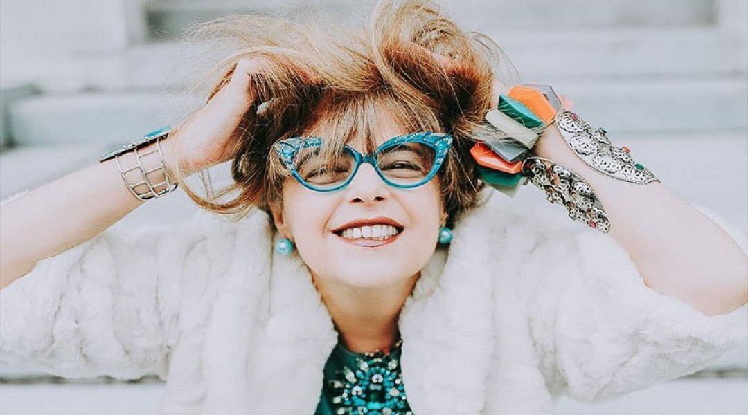 Smiling person wearing colorful clothes and glasses