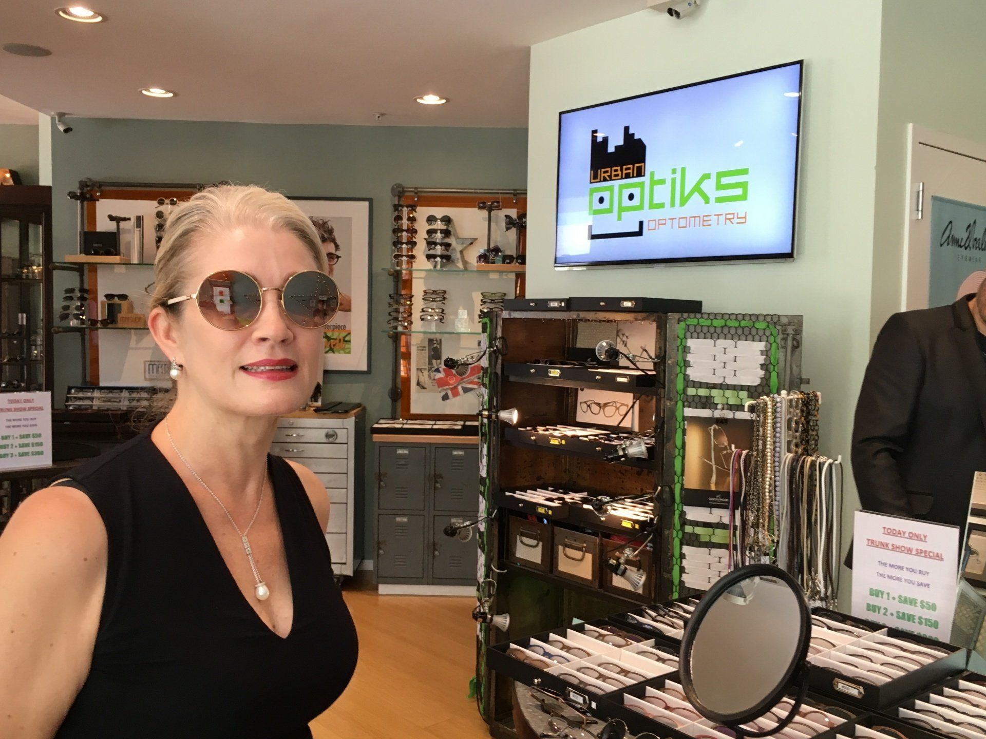 Woman trying on sunglasses at Urban Optiks Optometry at 2016 trunk show event