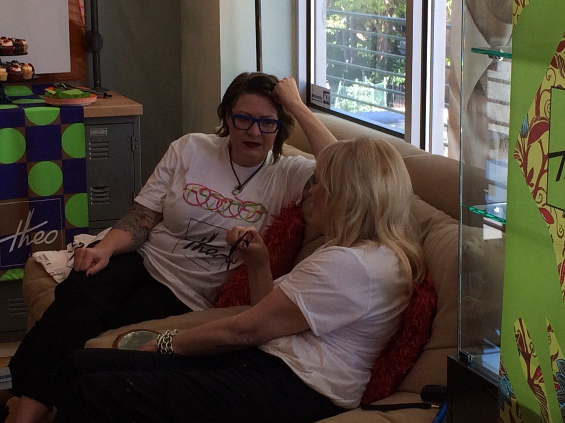 Two women chatting on sofa at Theo Trunk Show event at Urban Optiks