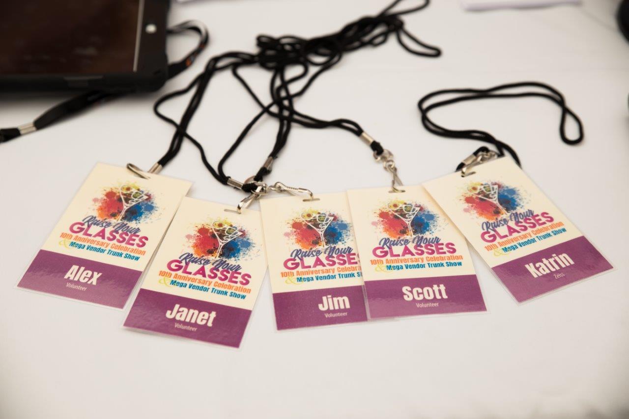 Colorful Raise Your Glasses vendor badges on white tablecloth