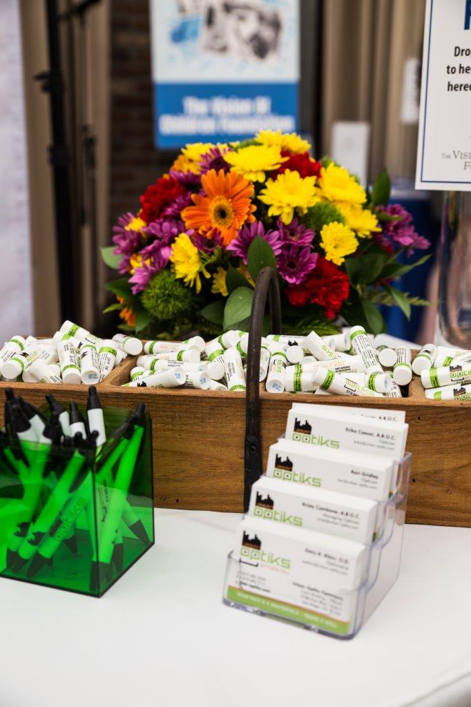 Flower arrangement and items with Urban Optiks Optometry logo at 2018 Raise Your Glasses