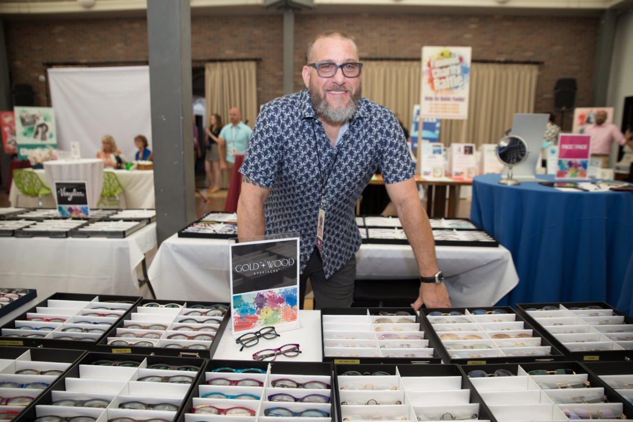 Gold and Wood vendor standing behind tabletop eyewear display at 2018 Raise Your Glasses