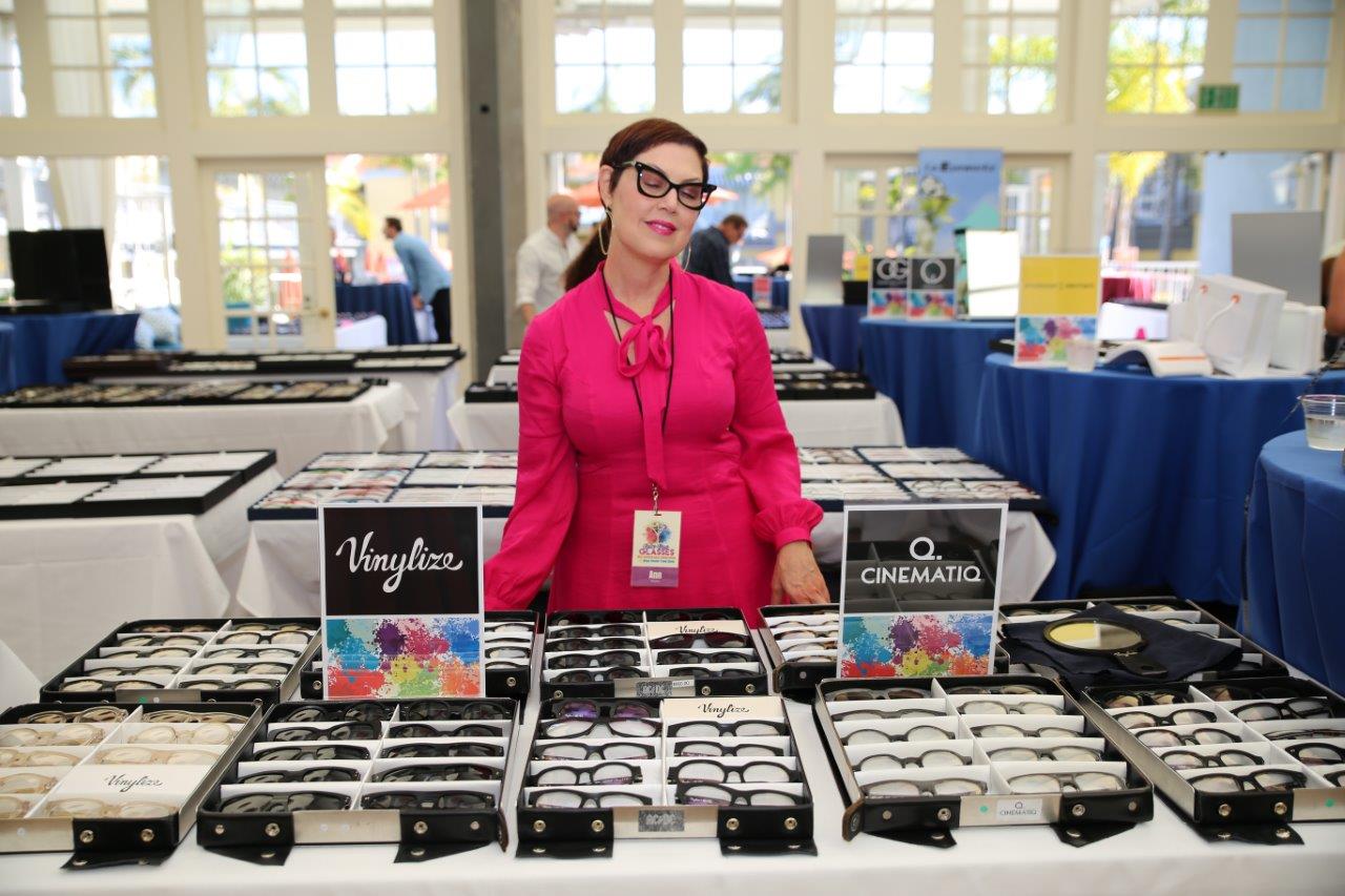 Vendor standing behind tabletop eyewear display at 2018 Raise Your Glasses