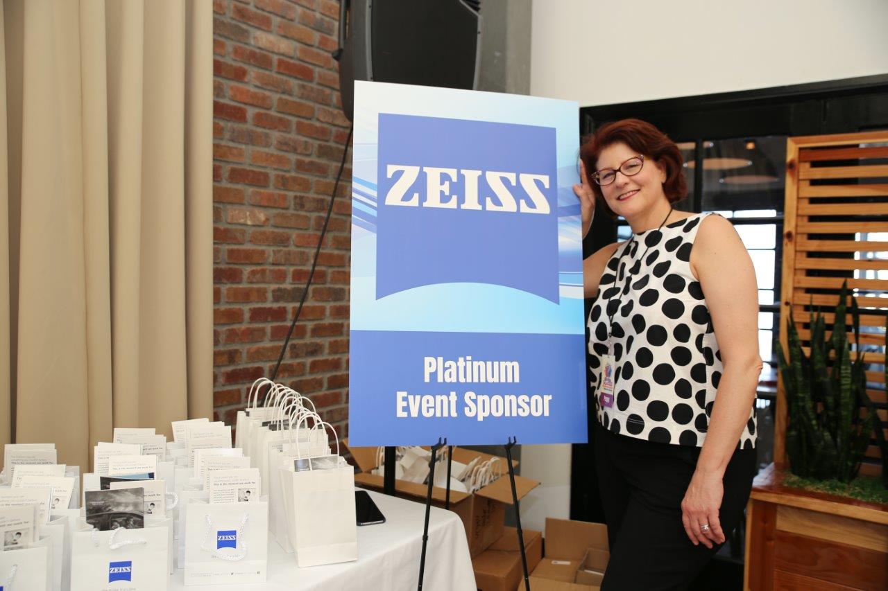 Person standing inside next to Zeiss banner at 2018 Raise Your Glasses
