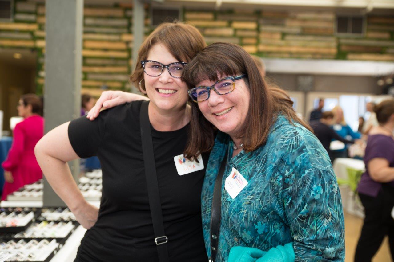 2 people wearing glasses smiling at Raise Your Glasses 2018 Event