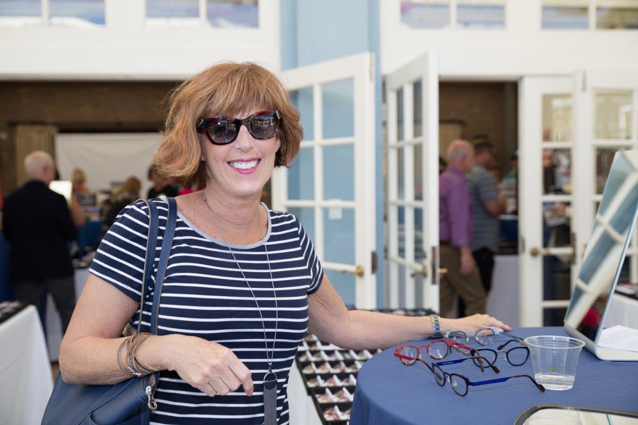 Guest trying on sunglass frames at outdoor table at Raise Your Glasses 2018 Event