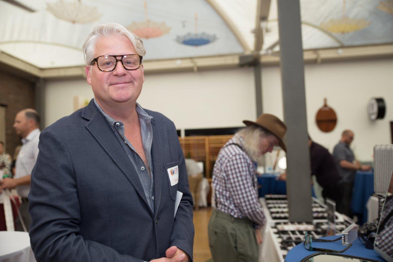 Smiling person and other attendees in background at Raise Your Glasses 2018 Event