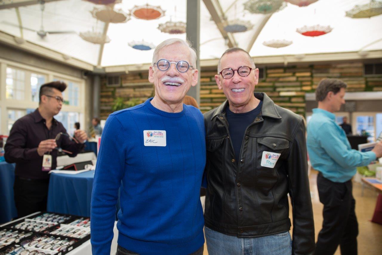 2 attendees in colorful glasses smiling for camera at Raise Your Glasses 2018 Event