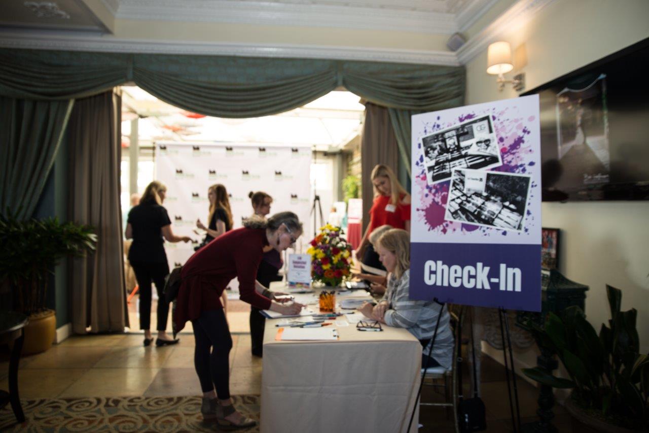 Attendee checking in at registration table at Raise Your Glasses 2018 Event