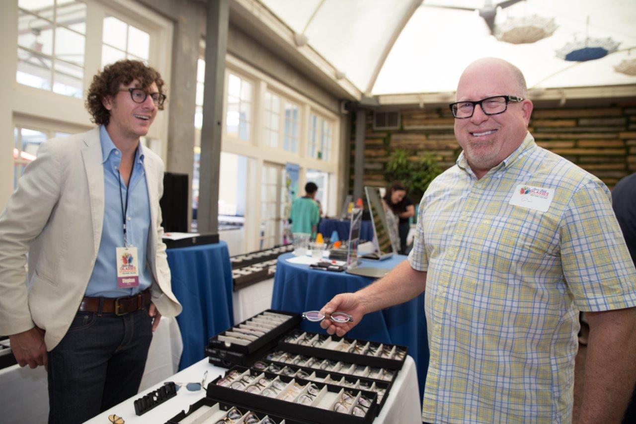 Guest holding frames and smiling during Raise Your Glasses 2018 Event