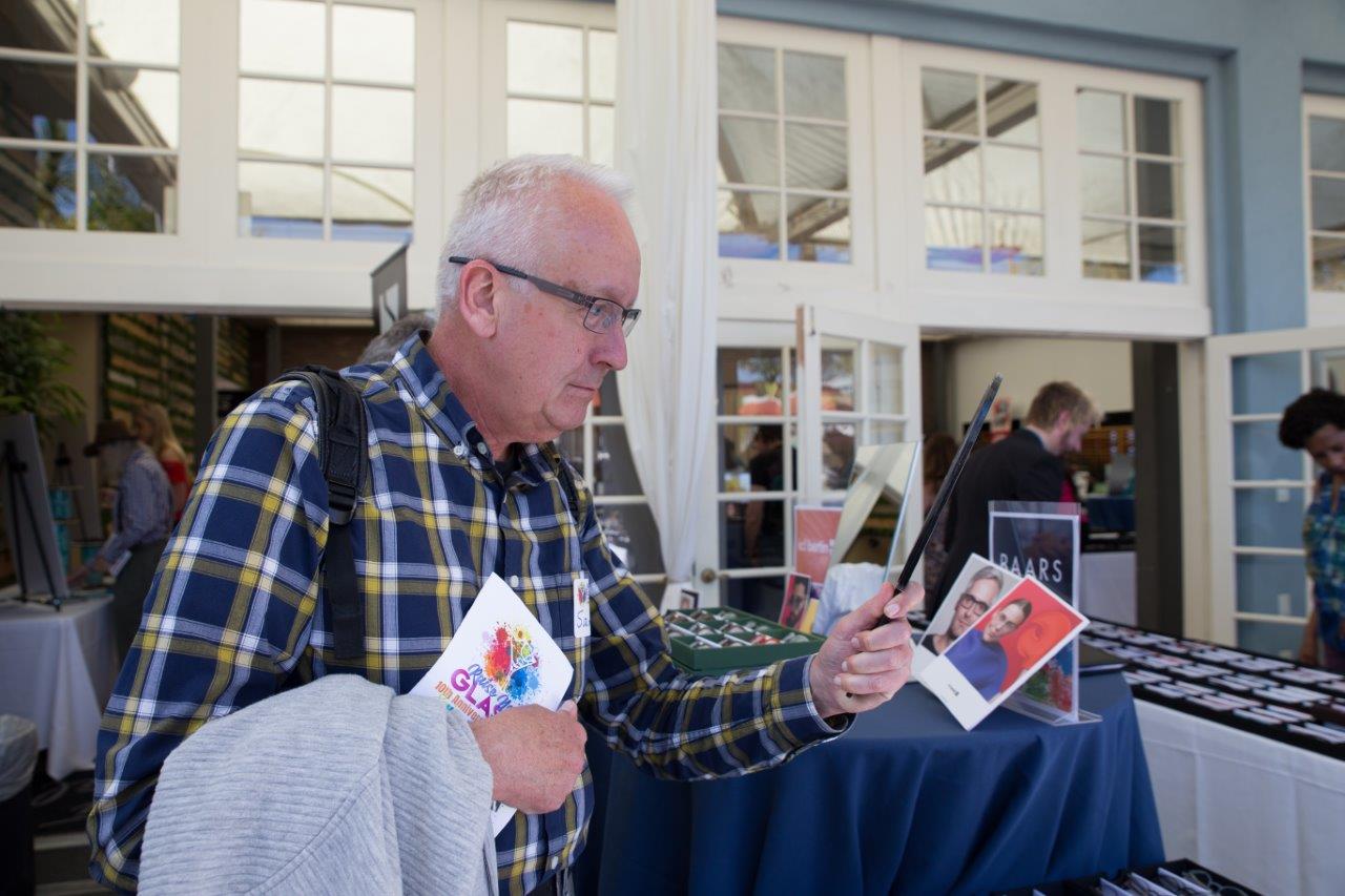 Person looking in mirror while trying on glasses during Raise Your Glasses 2018 Event
