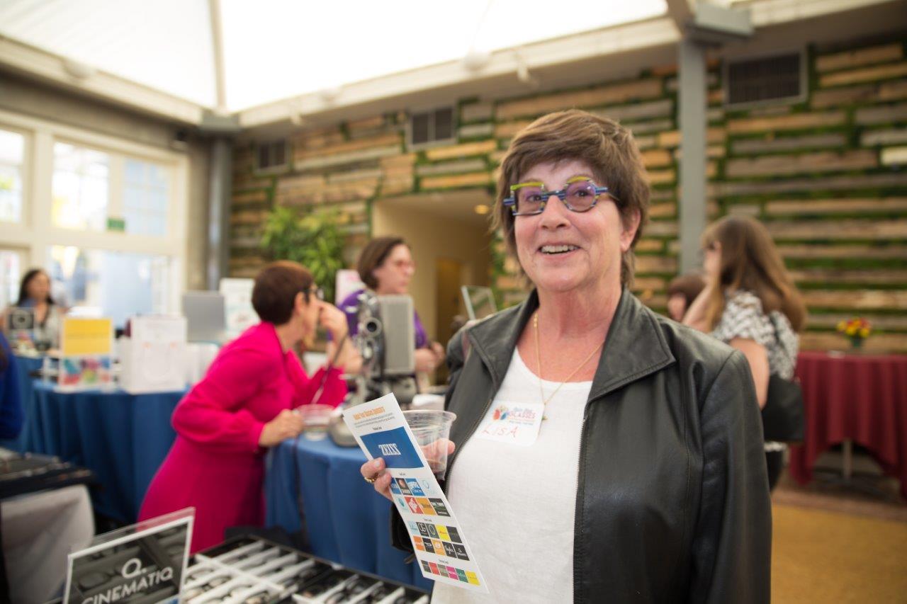 Woman wearing glasses and holding event booklet during Raise Your Glasses 2018 Event
