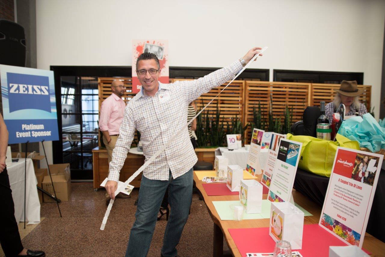 Person standing indoors holding a long strand of drawing tickets at Raise Your Glasses 2018 Event