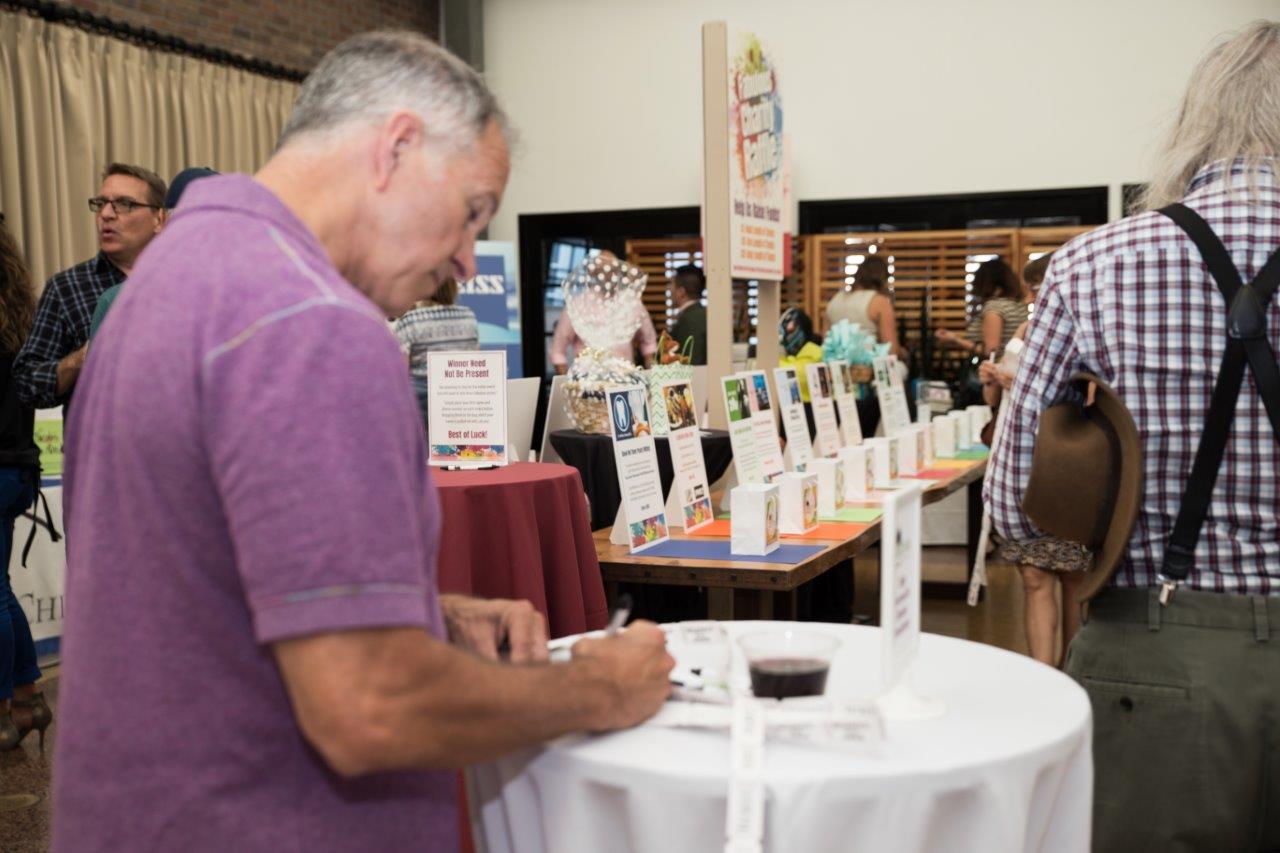 Person writing on drawing tickets at Raise Your Glasses 2018 Event