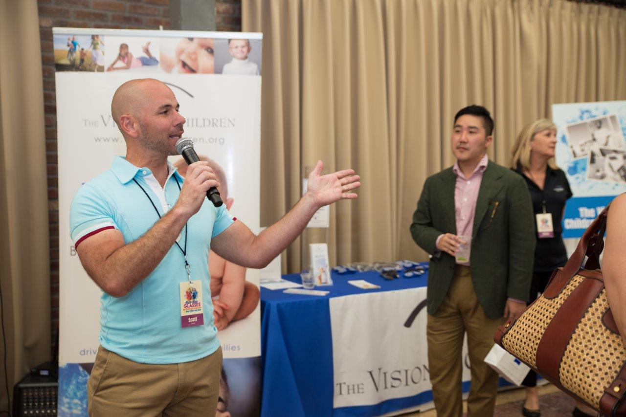 Person talking on microphone at Raise Your Glasses 2018 Event