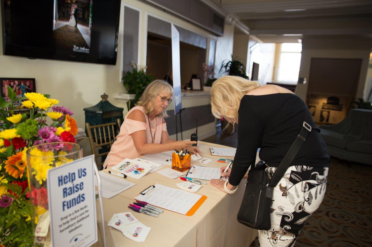 Person signing in at reception table at Raise Your Glasses 2018 Event
