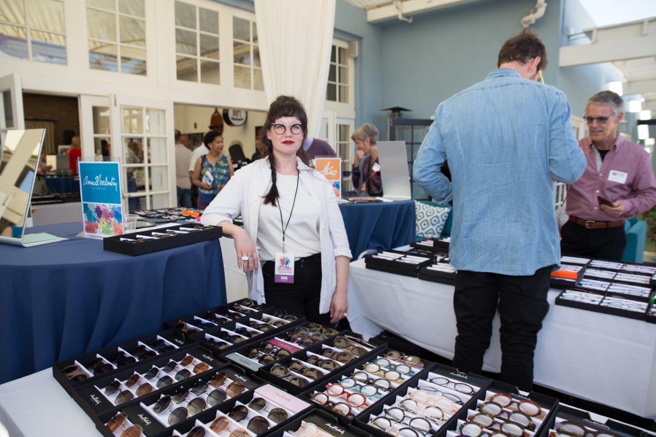 Vendor standing behind to tabletop display of frames at Raise Your Glasses 2018 Event