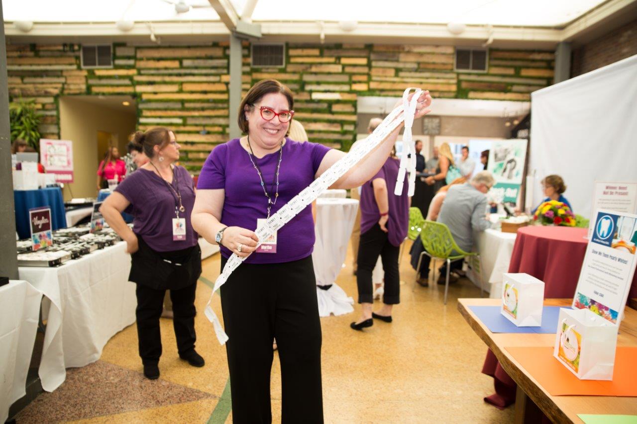 Person in purple shirt holding a long strand of drawing tickets at Raise Your Glasses 2018 Event