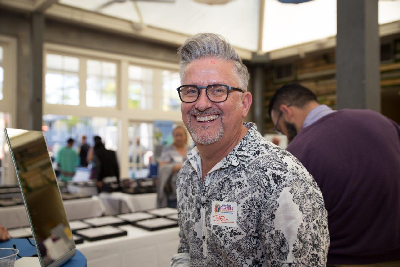 Man in glasses smiling at Raise Your Glasses 2018 Event