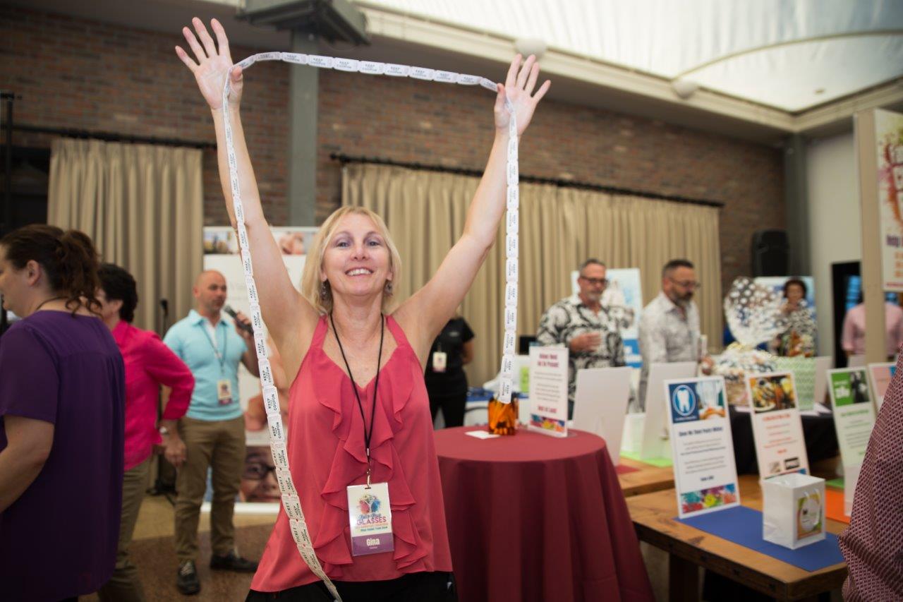 Woman holding a long strand of drawing tickets at Raise Your Glasses 2018 Event