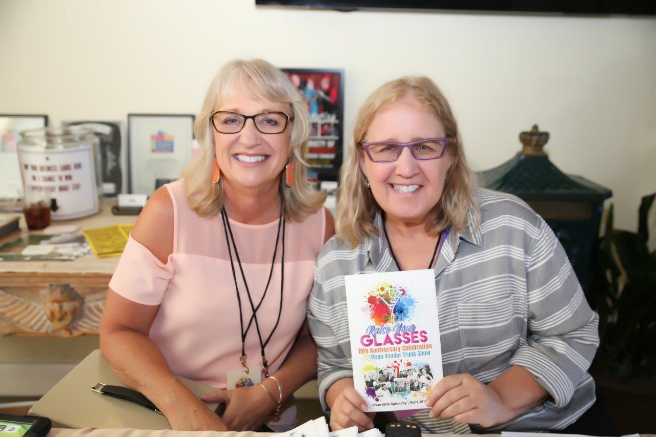 2 people smiling and holding event booklet at Raise Your Glasses 2018