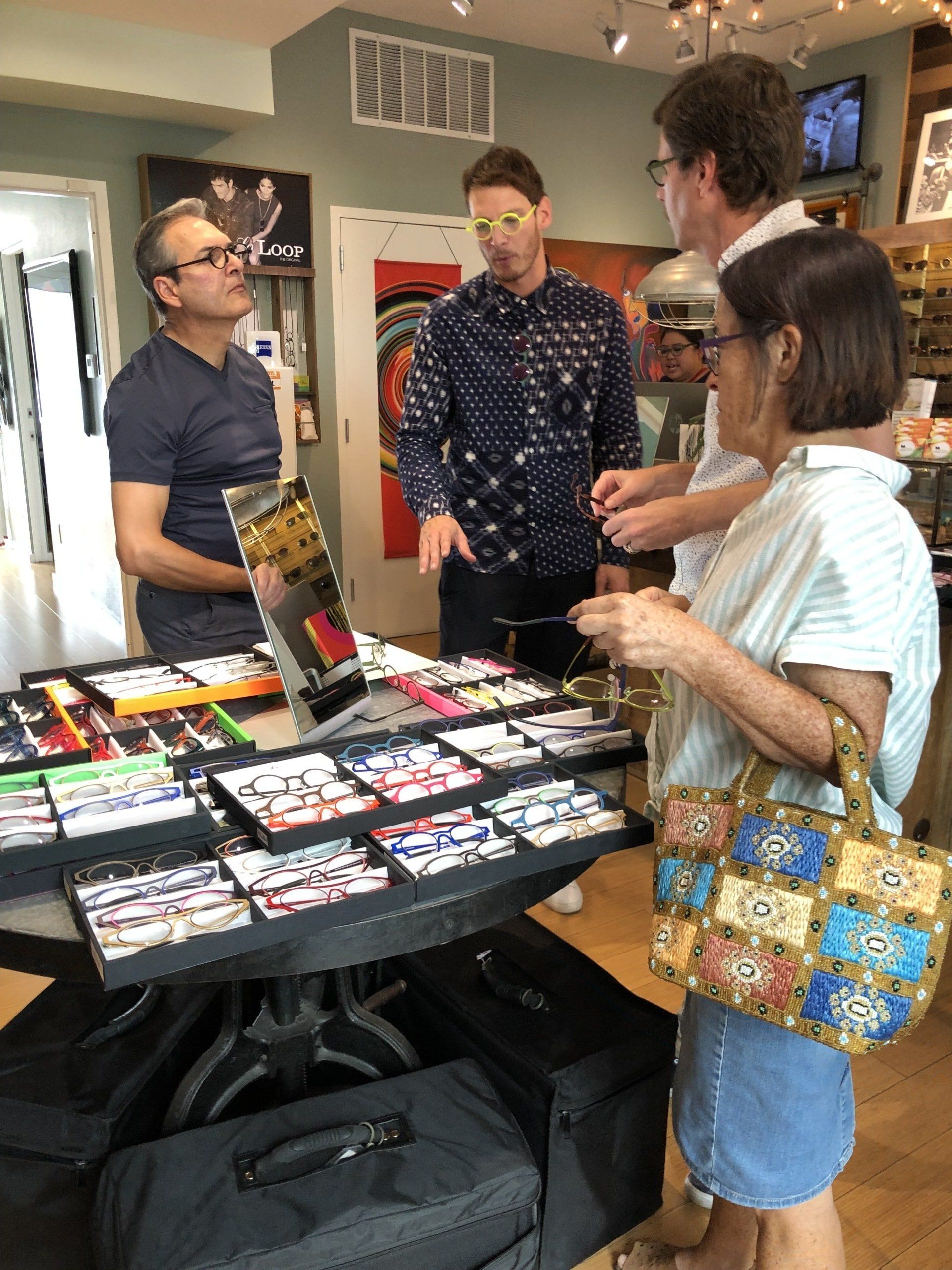 Four people looking at display cases of Theo frames at Theo Trunk Show Event