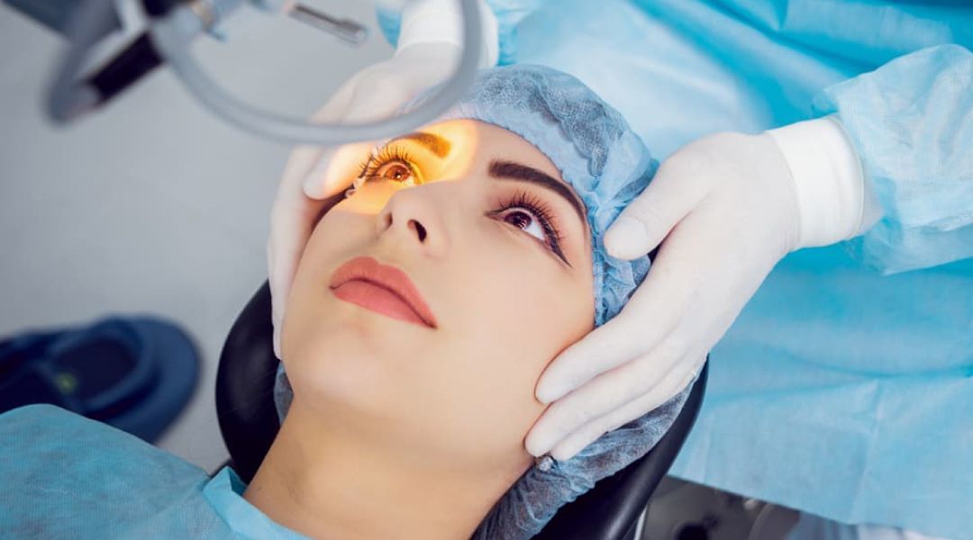 A doctor holding the head of a woman lying in an surgical chair with a laser light shinning on her