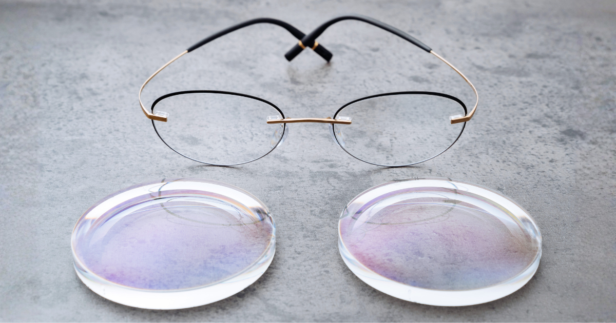 Wire-rimmed glasses sitting on a gray surface with two thick, round eyeglass lenses.