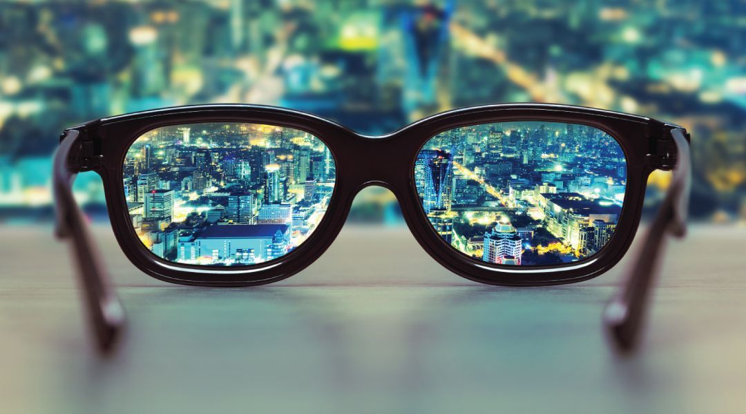 Pair of glasses in front of a city skyline at night in the background