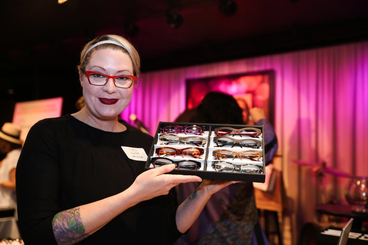 Woman holding up a box with eyeglass frames at Raise Your Glasses event