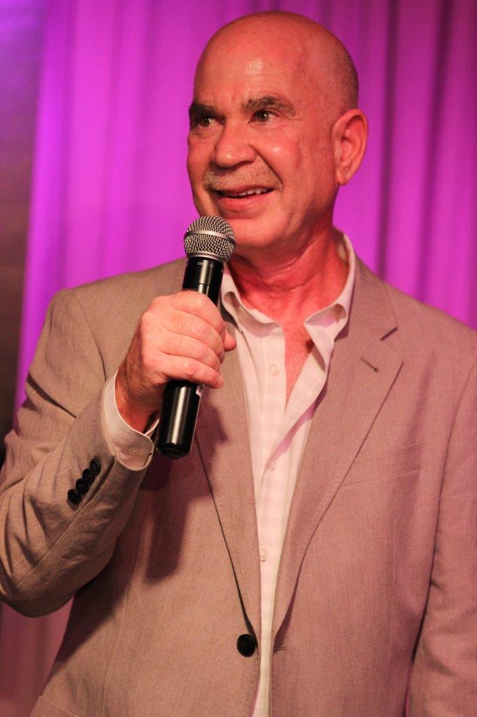 Dr. Klein onstage with microphone at Raise Your Glasses event
